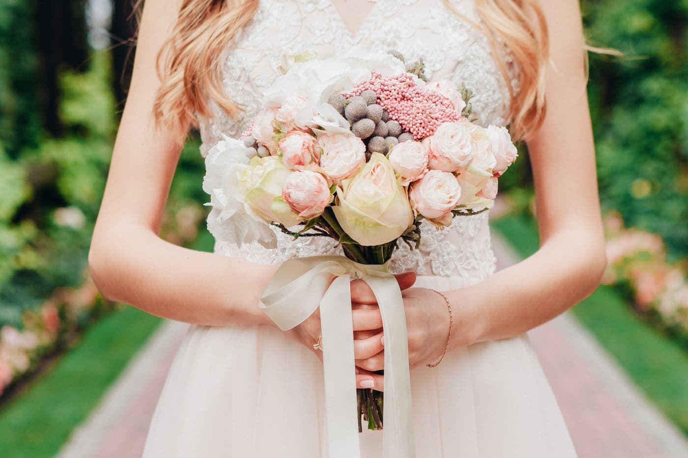 A bride holding a bouquet of blush and cream roses